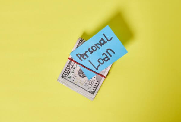Personal Loan writtern on a post it note attached to roll of bills